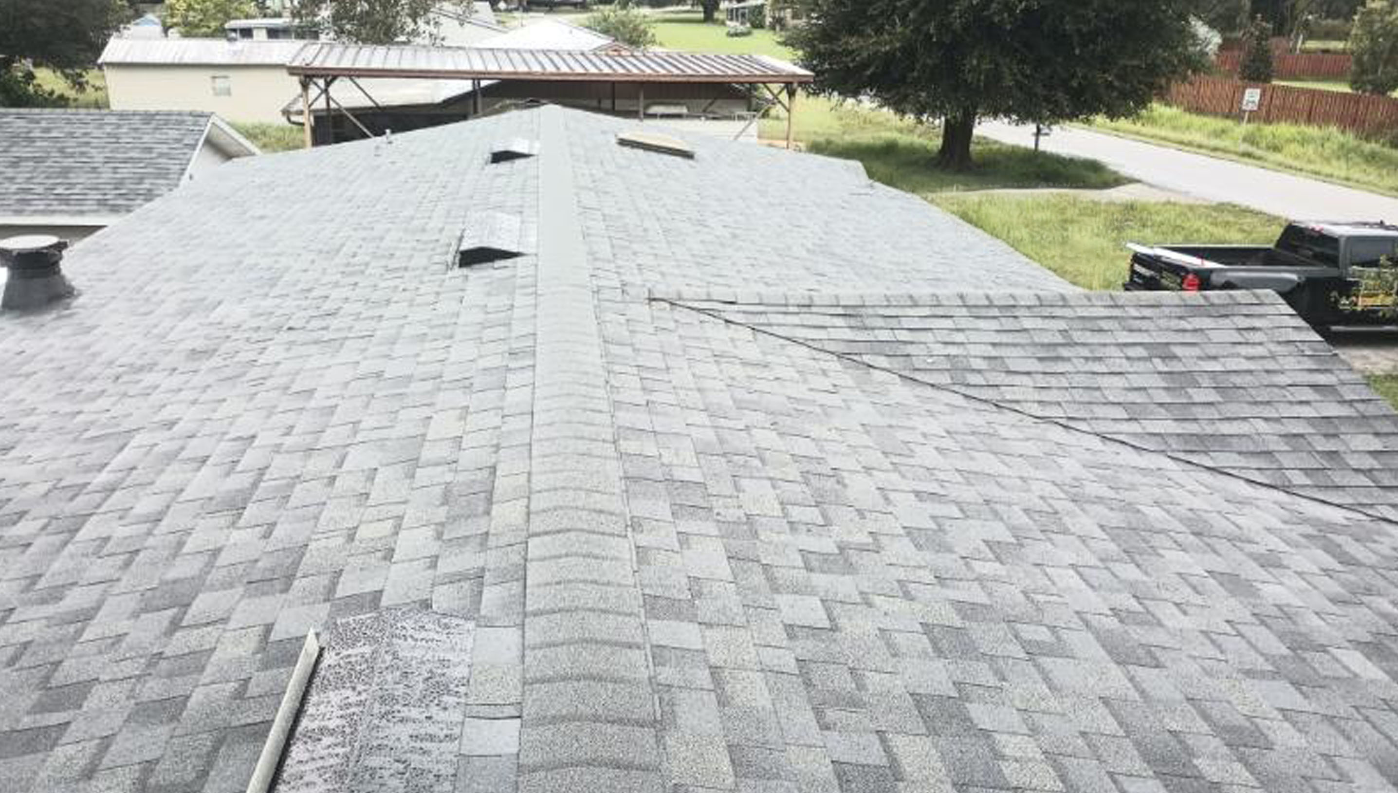 A rooftop with gray asphalt shingles and black roof vents.