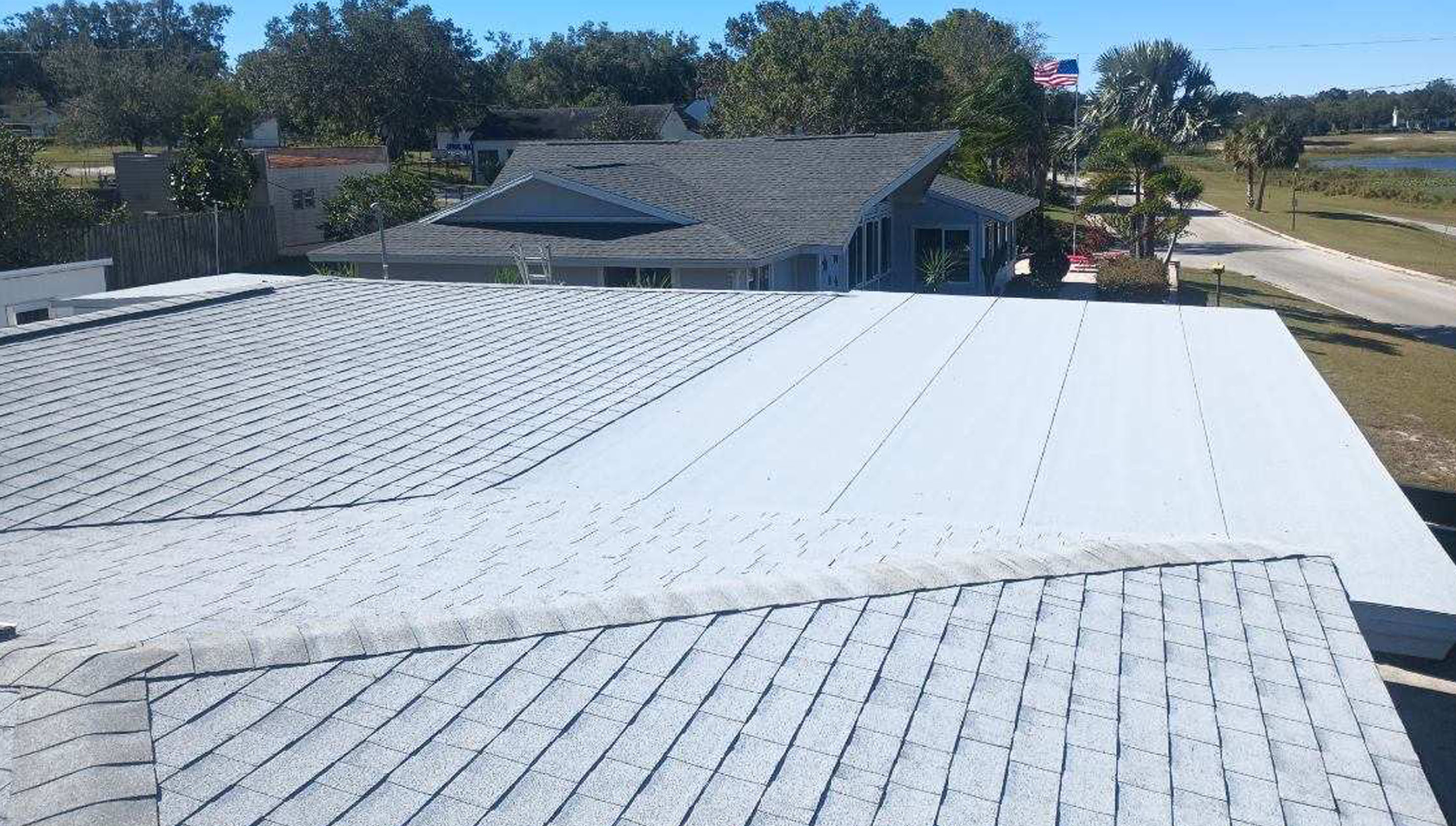 An elevated view of a rooftop with asphalt shingles and smooth surfaces.