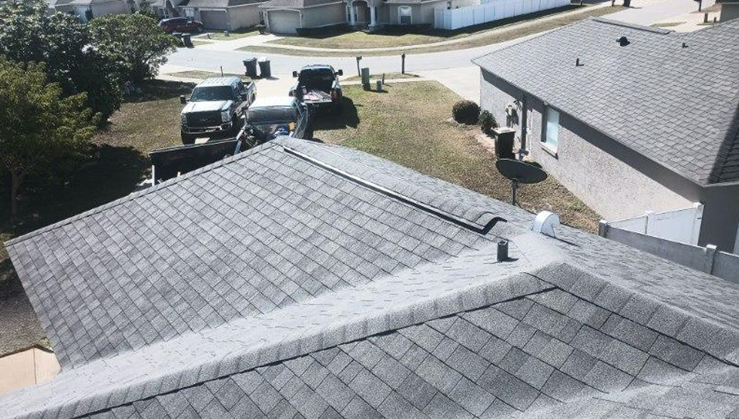 A view of a residential neighborhood from a gray shingled roof.