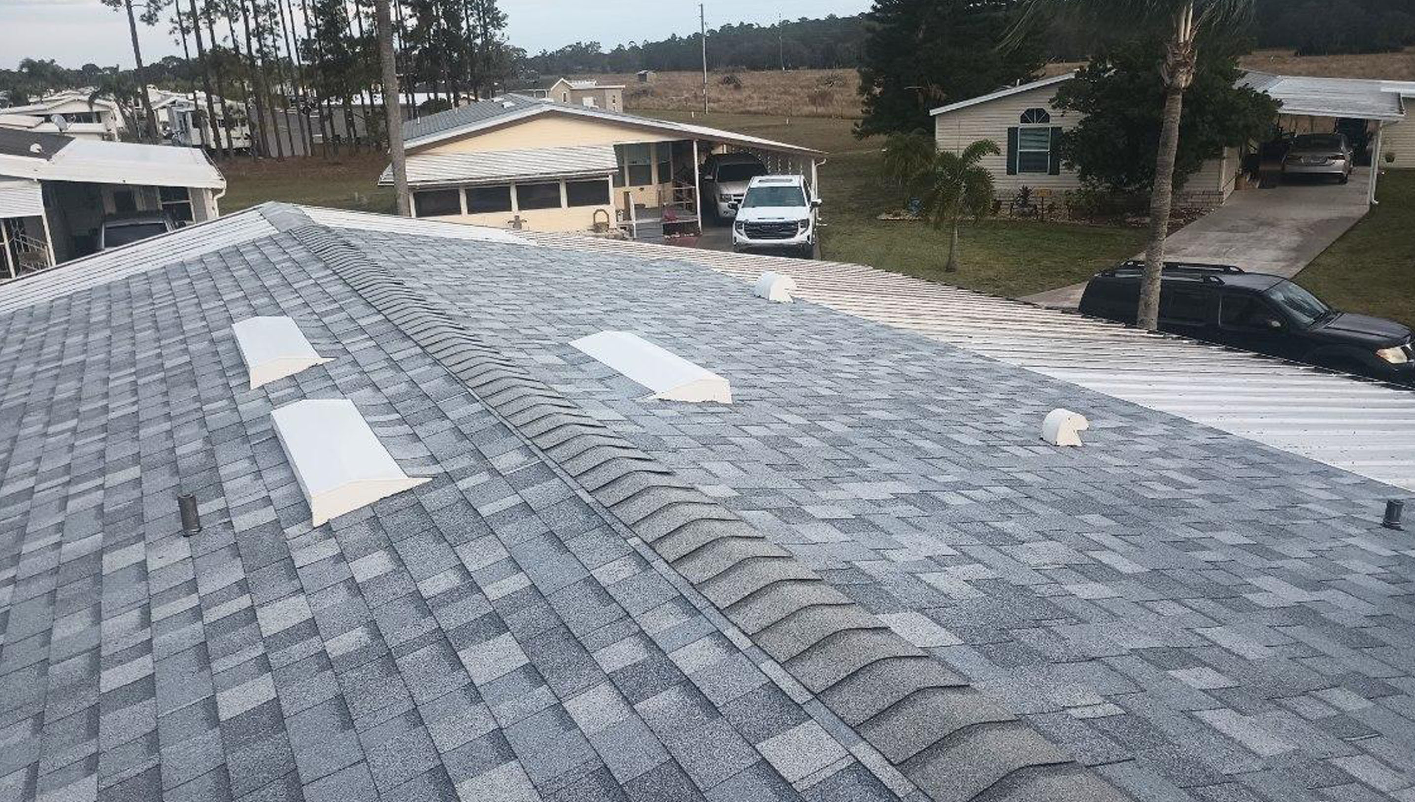 A residential roof with gray shingles and white vent caps.